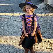 Naomi joined the competition — help win amazing prizes! child, costume, witch_hat, purple_dress, black_bucket, smiling, curly_hair, boots, outdoor, driveway, concrete, sunlight, shadow, halloween, trick_or_treat, festive, young_girl, holiday, cute, portrait