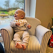 Theo joined the competition — help win amazing prizes! baby, child, armchair, striped, bib, clothing, indoor, window, foot, smile, happy, person, furniture, home, carpet, toy, hand, head, face, cozy