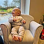 baby, child, armchair, striped, bib, clothing, indoor, window, foot, smile, happy, person, furniture, home, carpet, toy, hand, head, face, cozy