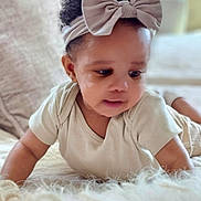 Meadow joined the competition — help win amazing prizes! baby, child, headband, bow, curly_hair, infant, cute, indoors, soft_lighting, fluffy_surface, white_clothing, skin, portrait, lying_down, closeup, toddler, face, expression, candid, young