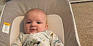 Myles is registered to the contest to win money with this photo: baby, infant, child, face, smile, onesie, bouncer, baby_bouncer, pillow, toy, blanket, carpet, cabinet, furniture, indoor, portrait, hand, playtime, nursery, cute