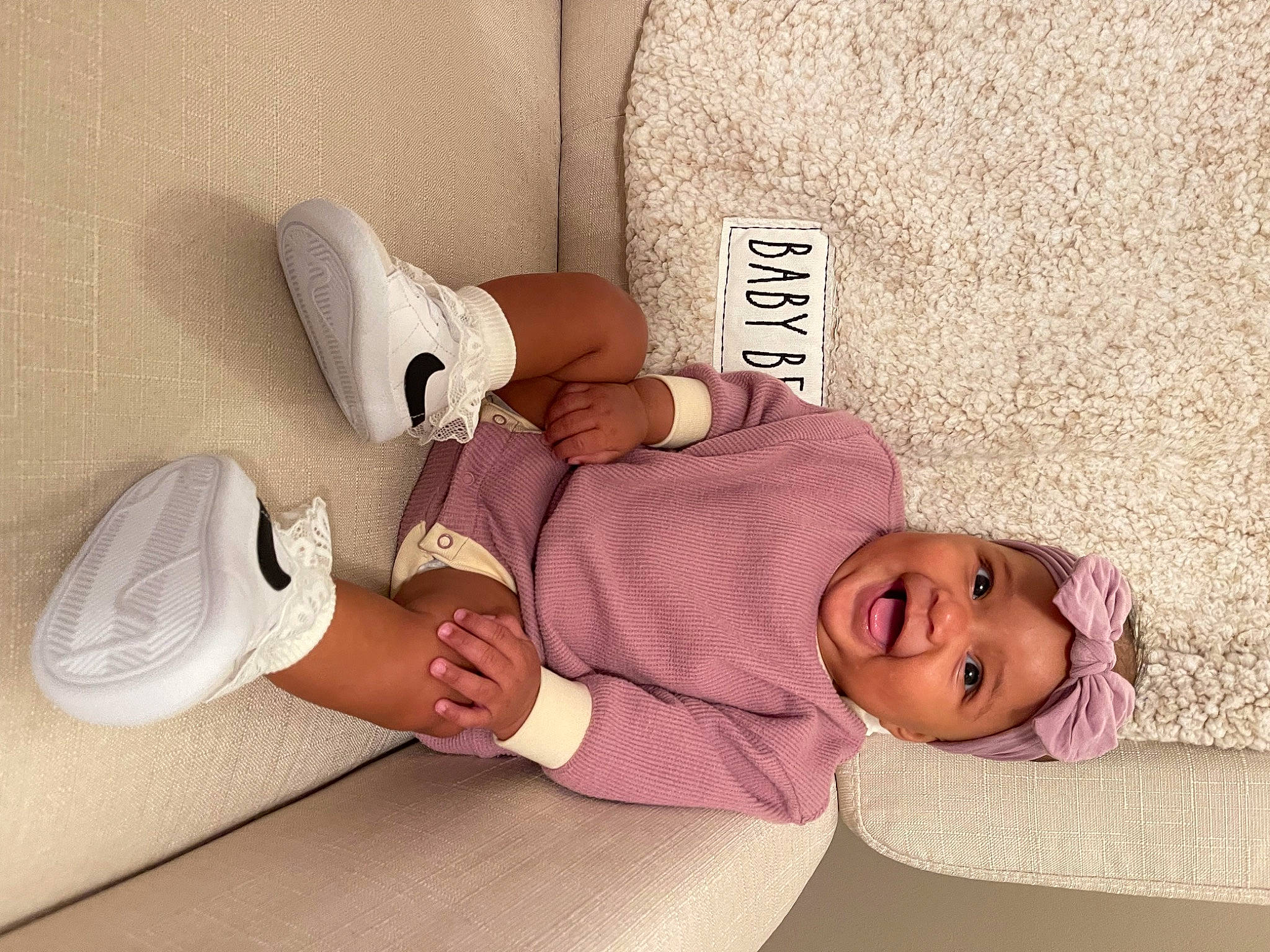 Nova is registered to the contest to win money with this photo: child, comfort, flooring, foot, happy, hat, headwear, human_leg, knee, linens, pattern, person, pink, room, serveware, sitting, sleeve, smile, sock, thigh