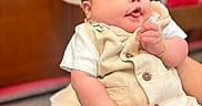 Leyden joined the competition — help win amazing prizes! baby, child, infant, cute, playful, tongue_out, beige_outfit, white_shirt, chubby_cheeks, hand, ring, bracelet, indoor, blurred_background, wooden_furniture, person, portrait, smile, holding, closeup