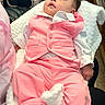 Leyden is registered to the contest to win money with this photo: baby, child, infant, pink_suit, white_shirt, blanket, clothing, cute, portrait, indoor, soft_texture, fluffy_blanket, small_hands, gazing_up, seated, adorable, curious_look, young, cozy, casual