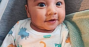 Ethan Paul a rejoint le concours — aidez-le/la à gagner de superbes lots ! adorable, baby, bedding, blanket, chubby_cheeks, close_up, cozy, dinosaur_print, fabric, gaze, human_face, infant, nursery, onesie, playful, portrait, sitting, smiling, soft_texture, wide_eyes