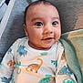 Ethan Paul a rejoint le concours — aidez-le/la à gagner de superbes lots ! baby, infant, smiling, wide_eyes, onesie, dinosaur_print, blanket, close_up, portrait, chubby_cheeks, cozy, bedding, fabric, human_face, adorable, sitting, soft_texture, nursery, gaze, playful
