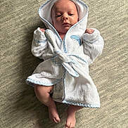 Eziriah is registered to the contest to win money with this photo: newborn, baby, infant, child, portrait, lying_down, hooded_robe, white_clothing, blue_trim, carpet, indoors, face, hands, feet, awake, centered, soft_texture, cozy, cute, photography