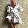 newborn, baby, infant, child, portrait, lying_down, hooded_robe, white_clothing, blue_trim, carpet, indoors, face, hands, feet, awake, centered, soft_texture, cozy, cute, photography