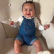 Alix a rejoint le concours — aidez-le/la à gagner de superbes lots ! baby, child, denim_overalls, white_shoes, armchair, smiling, happy, cute, indoor, seated, hair_tufts, clothing, infant, face, furniture, portrait, small_hands, legs, skin, cozy