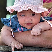 Freya joined the competition — help win amazing prizes! baby, child, hat, pink_hat, blue_clothing, arm, hand, finger, menu, table, wood, curious, face, portrait, cute, skin, person, infant, outdoor, blurred_background