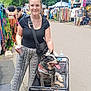 accessory, bag, bandana, can, casual, clothing, dog, festival, market, necklace, outdoor, pavement, people, shopping, smiling, summer, sunny, trees, wagon, woman