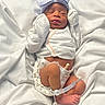 baby, bed, birth, blanket, bow, closed_eyes, diaper, face, feet, gloves, headband, hospital, infant, lying_down, medical_bracelet, newborn, onesie, portrait, sleeping, white_blankets