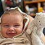 baby, smiling, blanket, hood, stuffed_animal, toy, sheep, plush, face, infant, cute, child, portrait, cozy, happy, person, indoors, soft, closeup, warm