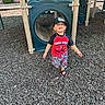 toddler, child, playground, slide, plastic, cap, sandals, smiling, outdoor, wood_chips, play_equipment, shorts, tshirt, person, daylight, fun, recreation, happy, young_child, casual_clothing