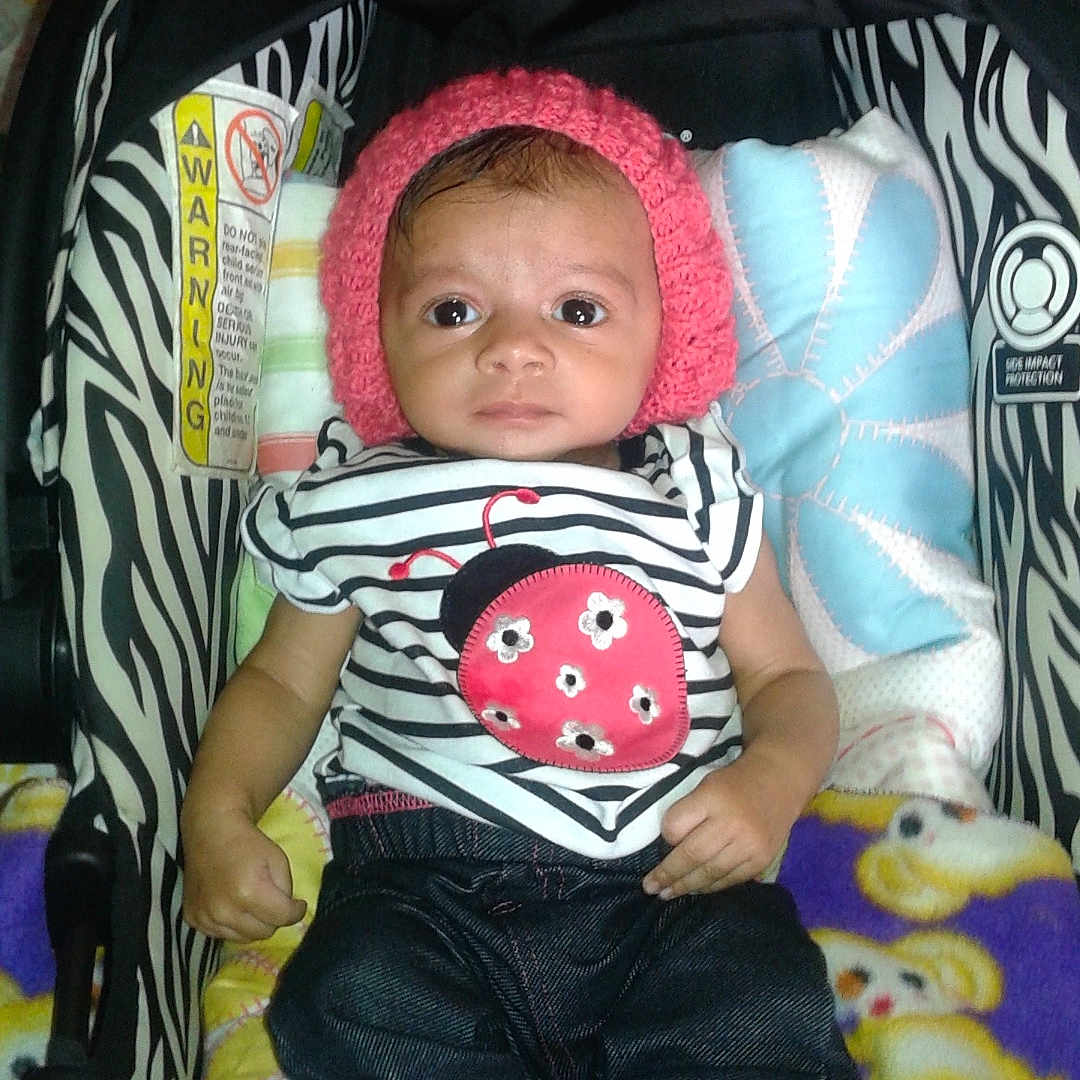 Kaylyn joined the competition — help win amazing prizes! baby, infant, child, stroller, pink_hat, striped_shirt, ladybug_design, jeans, white_shoes, blanket, cushion, zebra_pattern, indoor, cute, young_child, seated, clothing, footwear, headwear, portrait