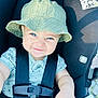 baby, child, bucket_hat, car_seat, blue_eyes, smiling, straps, clothing, cute, infant, face, hand, safety, seat_belt, expression, portrait, person, outdoor, happy, closeup