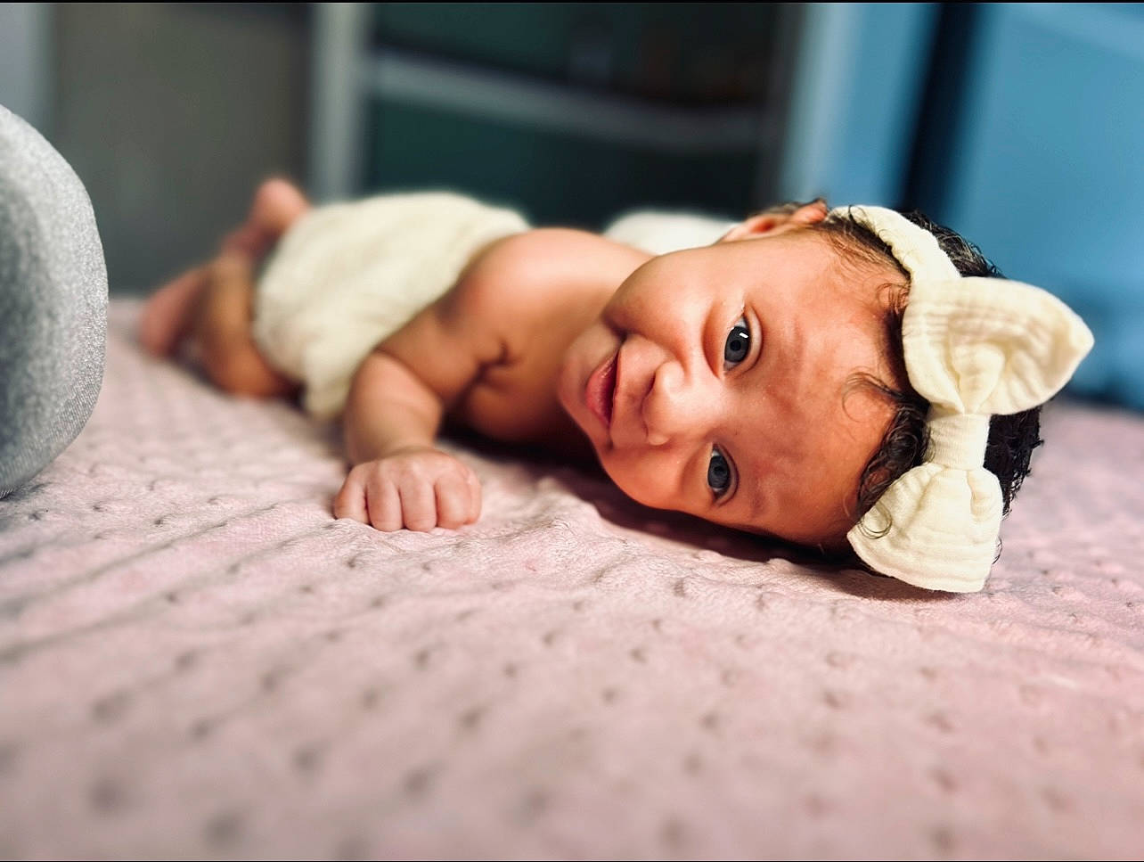 Elora is registered to the contest to win money with this photo: baby, baby_toddler_clothing, cheek, child, comfort, face, flash_photography, floor, flooring, fur, grass, hardwood, headpiece, headwear, linens, person, portrait_photography, room, sitting, skin