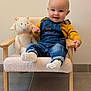 baby, child, denim_overalls, yellow_shirt, plush_toy, sheep_toy, chair, smile, happy, indoor, floor_tiles, socks, wooden_armrest, cozy, cute, portrait, infant, furniture, soft_texture, person