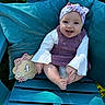 baby, infant, child, smiling, portrait, outdoor, chair, cushion, turquoise, headband, bow, overalls, shirt, sitting, milestone, four_months, wooden_sign, grass, sunlight, happy