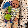 Josie is registered to the contest to win money with this photo: baby, baby_seat, blue_toy, child, colorful, elephant_pattern, green_toy, happy, indoors, infant, musical_toy, pajamas, playtime, portrait, pumpkin_pattern, seated, smiling, striped_clothing, stuffed_toy, toy