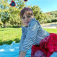 Jade a rejoint le concours — aidez-le/la à gagner de superbes lots ! blanket, blue_sky, casual_clothing, child, daylight, girl, grass, happy, headband, heart_antennae, kneeling, nature, outdoor, park, playful, red_tutu, smiling, striped_shirt, sunny, trees