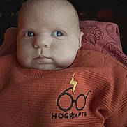Orion joined the competition — help win amazing prizes! baby, infant, face, sweater, clothing, orange, portrait, child, cute, indoors, person, young, head, eyes, expression, cozy, soft_light, sitting, background, curious