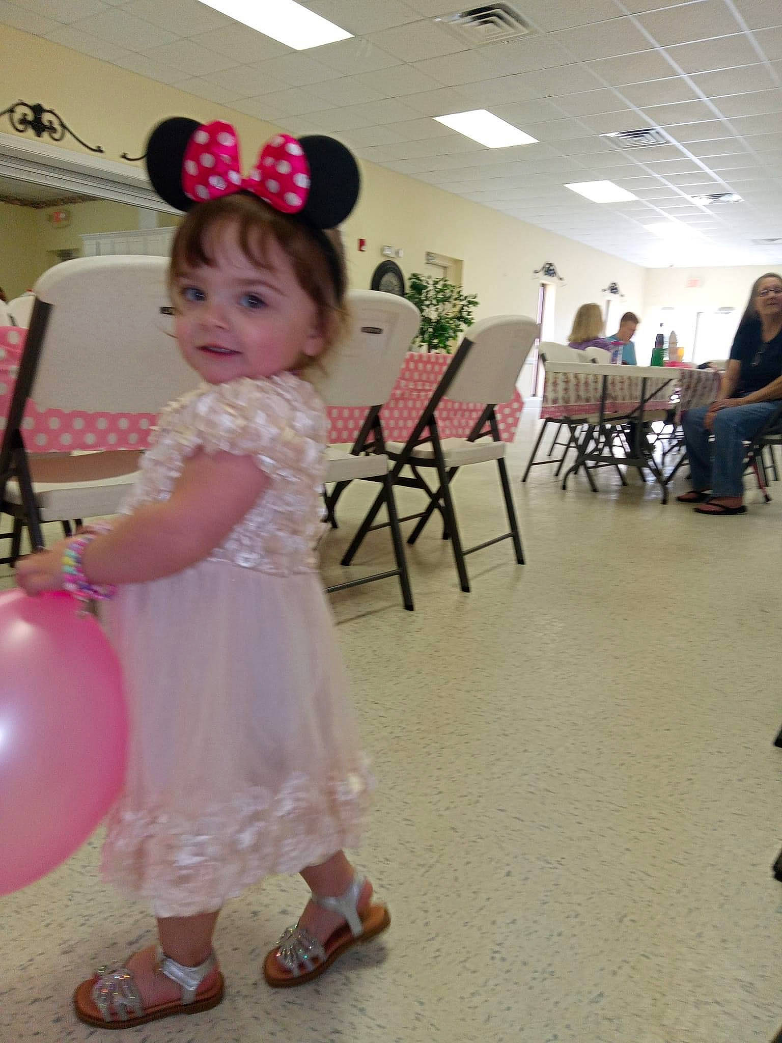 Persephone is registered to the contest to win money with this photo: baby, baby_toddler_clothing, balloon, chair, child, event, flooring, fun, happy, hat, leisure, magenta, party_supply, person, pink, recreation, room, sandal, skin, smile