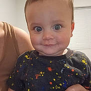 Jimmy is registered to the contest to win money with this photo: baby, child, person, smile, face, indoor, window, blind, adult_hand, colorful_shirt, short_hair, skin, happy, cute, portrait, closeup, holding, expression, eyeballs, casual_clothing