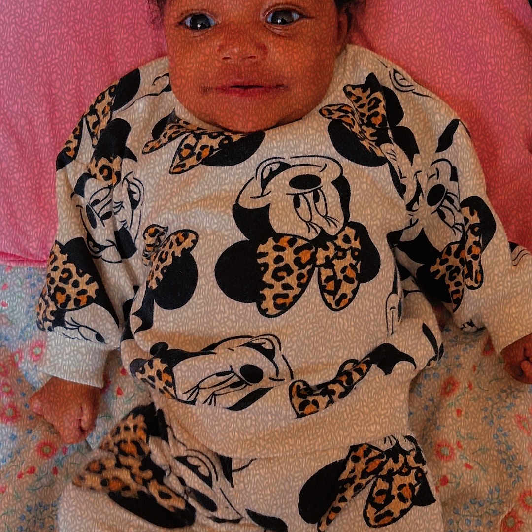 Kali joined the competition — help win amazing prizes! baby, infant, child, mickey_mouse, leopard_print, bow, headwear, blanket, clothing, patterned_clothing, smiling, lying_down, cute, portrait, indoor, person, toddler, fabric, colorful, soft
