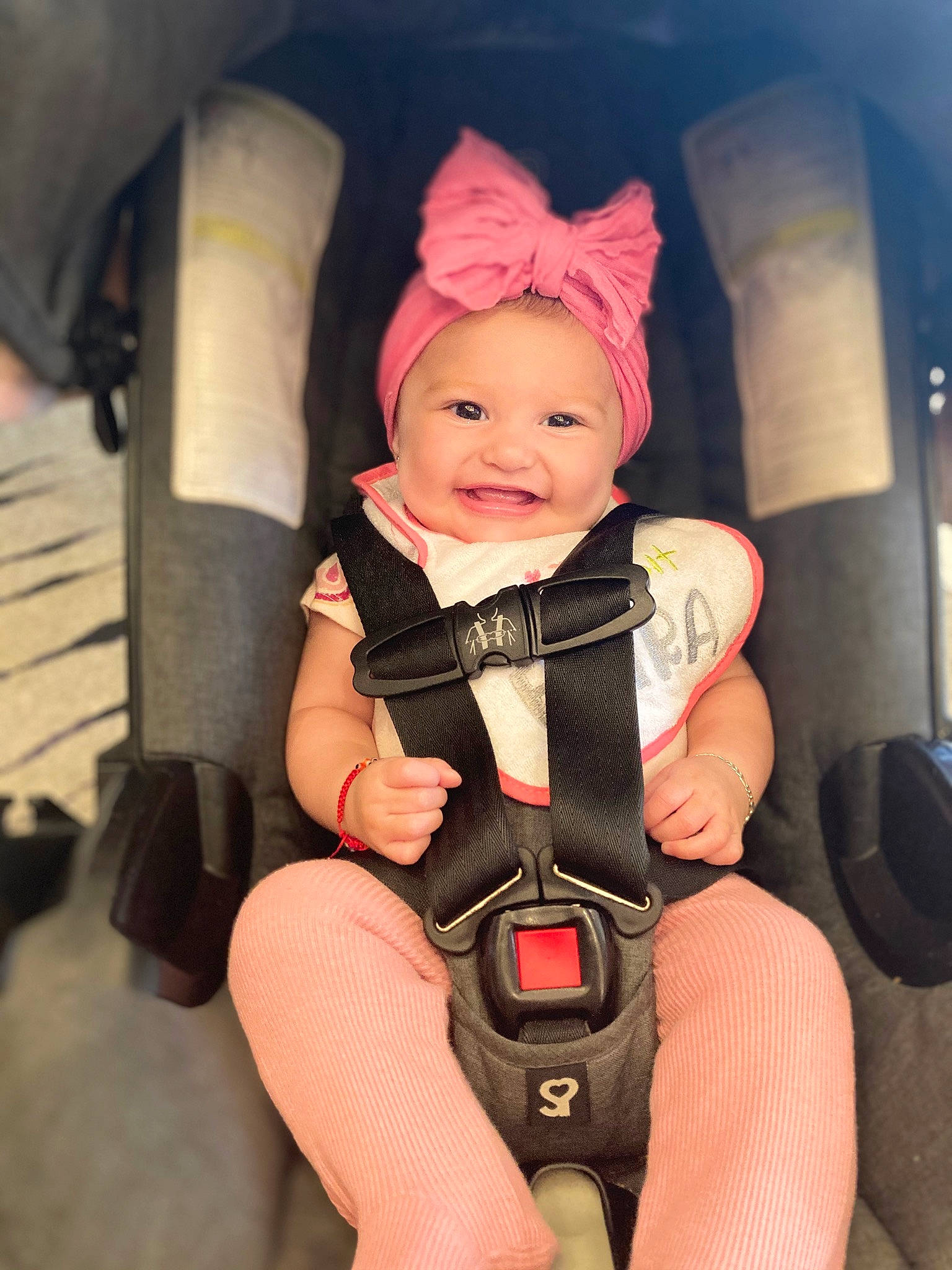 Norma is registered to the contest to win money with this photo: auto_part, baby, baby_carriage, baby_products, baby_toddler_clothing, car_seat, chair, cheek, comfort, happy, headwear, helmet, human_body, human_leg, person, personal_protective_equipment, pink, seat_belt, service, smile