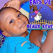 Doune a rejoint le concours — aidez-le/la à gagner de superbes lots ! child, toddler, smiling, blue_shirt, cuddling, blanket, patterned_blanket, arm, hand, face, bedtime, cartoon_sticker, text_overlay, sleepy, indoor, cute, closeup, portrait, happy, skin