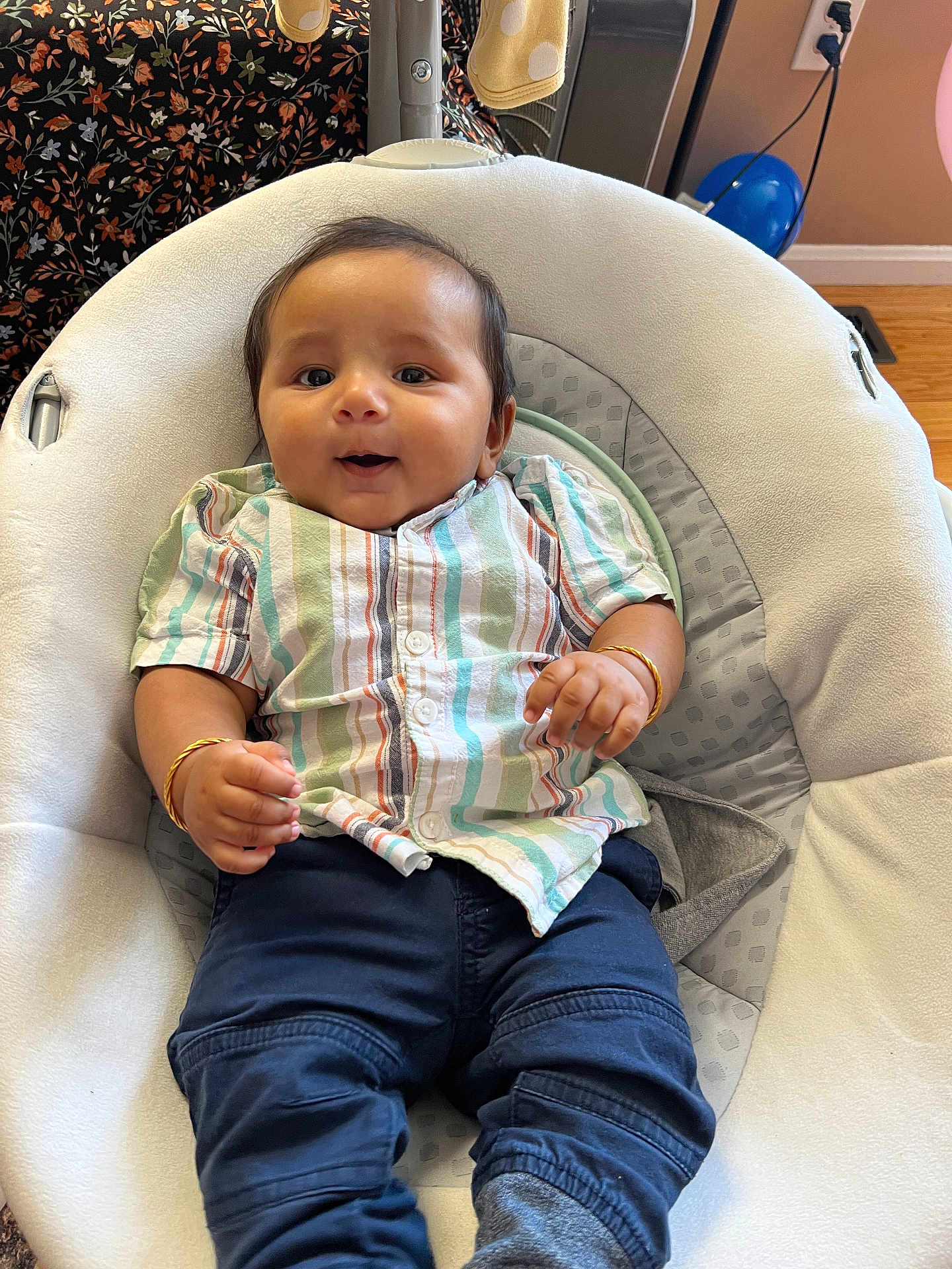 Madhav joined the competition — help win amazing prizes! baby, infant, smiling, striped_shirt, blue_pants, bracelets, baby_seat, cushion, indoors, happy, child, casual_clothing, comfort, cute, portrait, person, young_child, home, floor, wooden_floor