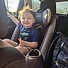 toddler, child, car_seat, car_interior, sunlight, smiling, happy, seatbelt, shorts, blue_shirt, backseat, window, daylight, hair, person, vehicle, safety, casual_clothing, travel, young_child