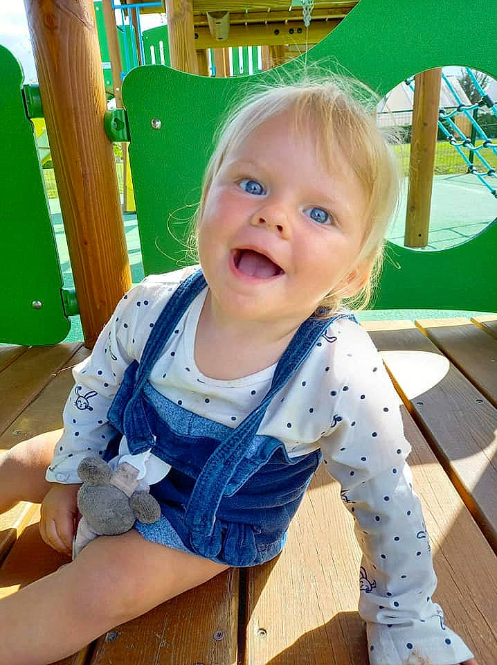 Lya participe au concours pour gagner de l'argent avec cette photo : baby, baby_products, baby_toddler_clothing, child, mouth, outdoor_play_equipment, overall, person, playground, polka_dot, toddler, tongue