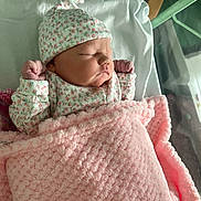 Ocean is registered to the contest to win money with this photo: newborn, baby, sleeping, blanket, pink, hat, hospital, bassinet, infant, cozy, cute, child, soft, floral, clothing, peaceful, portrait, wrapped, resting, indoors
