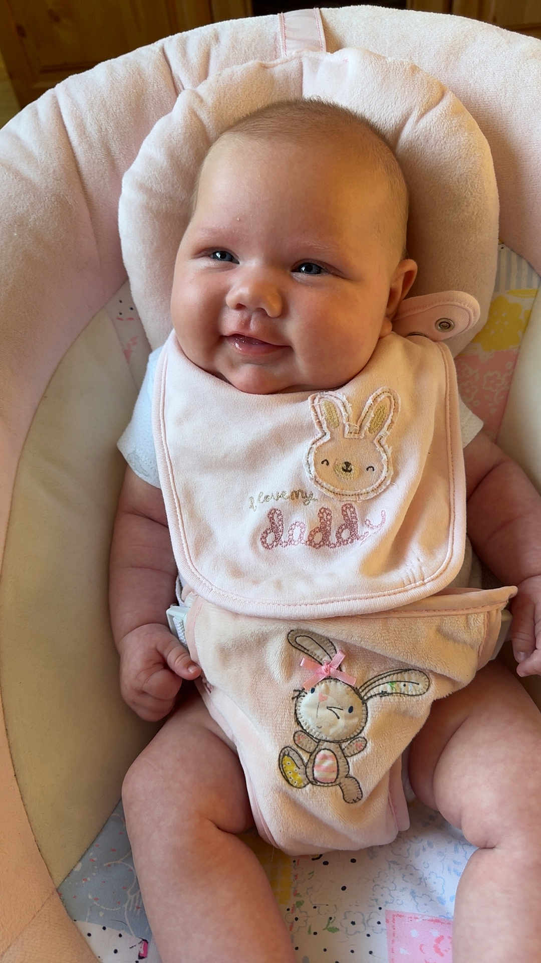 Ocean is registered to the contest to win money with this photo: baby, infant, smiling, pink, bib, bunny, plush, baby_seat, cute, happy, child, clothing, diaper_cover, chubby_cheeks, skin, head, face, seated, indoors, soft_lighting