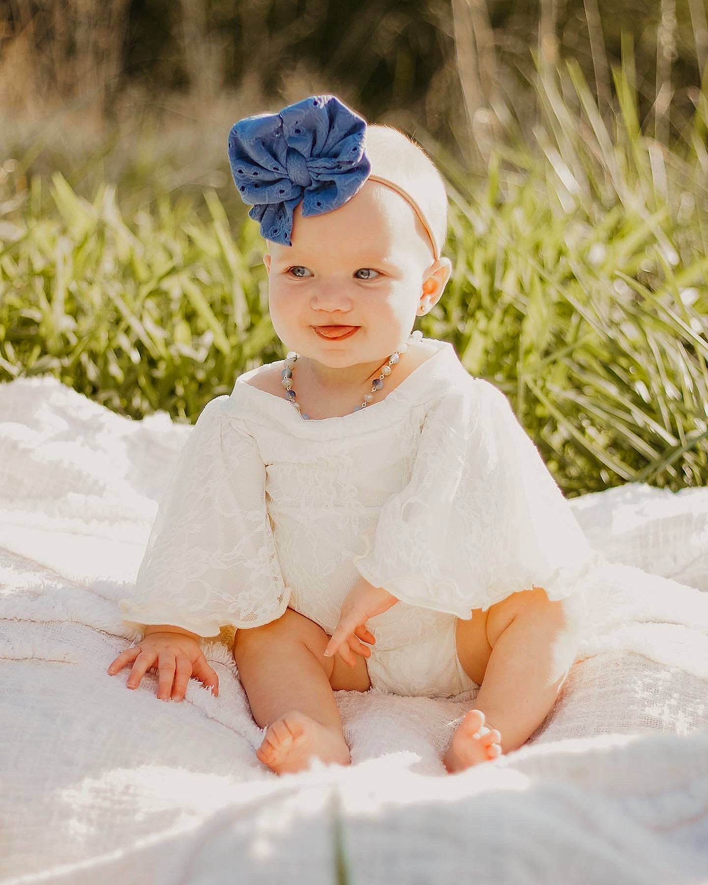 Hadley is registered to the contest to win money with this photo: baby, baby_toddler_clothing, bridal_accessory, cap, dress, eye, flash_photography, fun, grass, hair_accessory, happy, headband, headgear, headpiece, headwear, human_body, outerwear, people_in_nature, person, plant