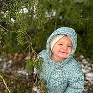 Ella a rejoint le concours — aidez-le/la à gagner de superbes lots ! toddler, child, smile, winter_clothing, jacket, hat, gloves, outdoor, nature, pine_tree, snow, greenery, playful, forest, cold_weather, happy, young_child, exploration, seasonal, portrait