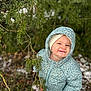 toddler, child, smile, winter_clothing, jacket, hat, gloves, outdoor, nature, pine_tree, snow, greenery, playful, forest, cold_weather, happy, young_child, exploration, seasonal, portrait