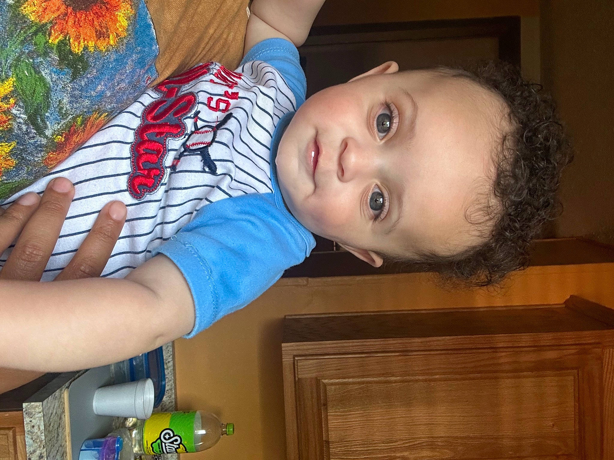 Ezra is registered to the contest to win money with this photo: arm, baby, baby_toddler_clothing, cheek, child, dress, electric_blue, finger, hand, happy, head, human_leg, nose, organ, pattern, person, plant, sleeve, smile, toddler