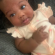 Trinity is registered to the contest to win money with this photo: baby, child, clothing, couch, curious, cute, expression, eyes, face, hand, indoors, infant, peach_outfit, person, portrait, sitting, skin, soft_light, texture, young