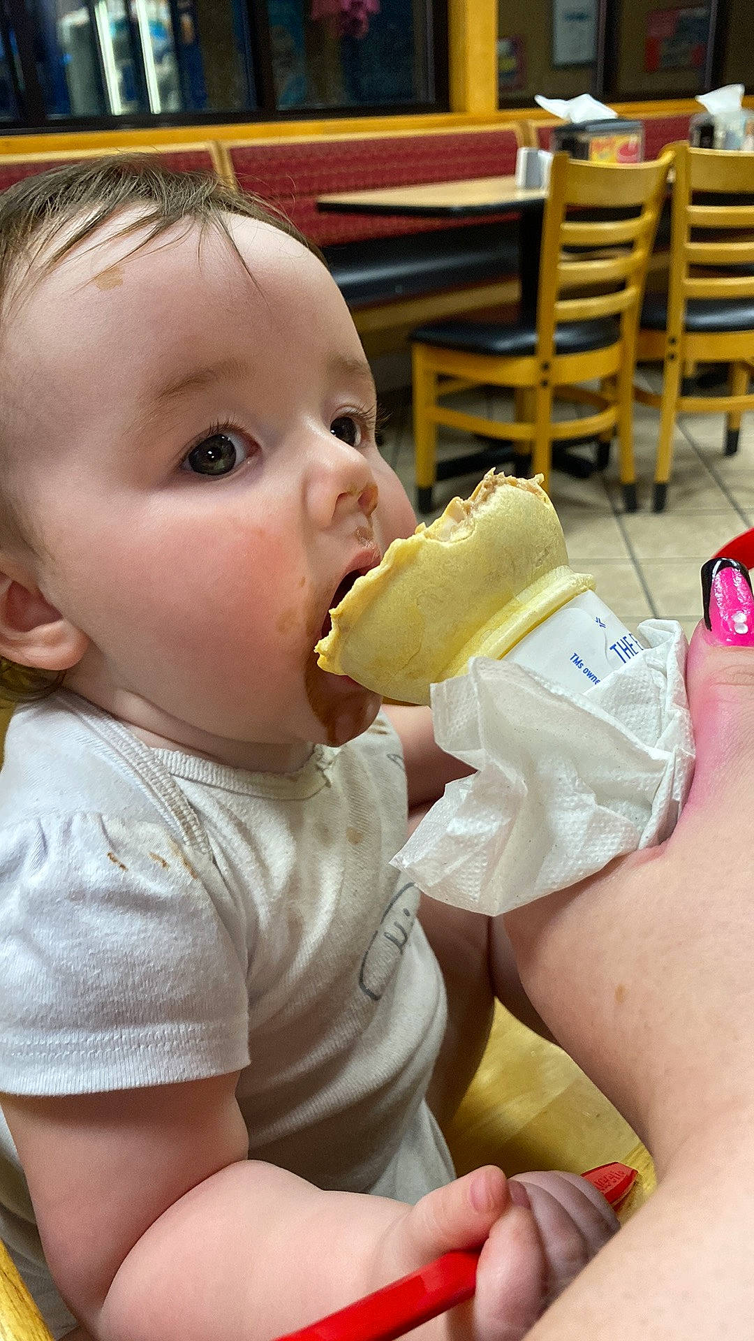 Paisleigh is registered to the contest to win money with this photo: baby, baby_toddler_clothing, biting, chair, child, drinking, drinkware, finger, food, food_craving, fun, gesture, happy, junk_food, mouth, nose, person, skin, sweetness, thumb