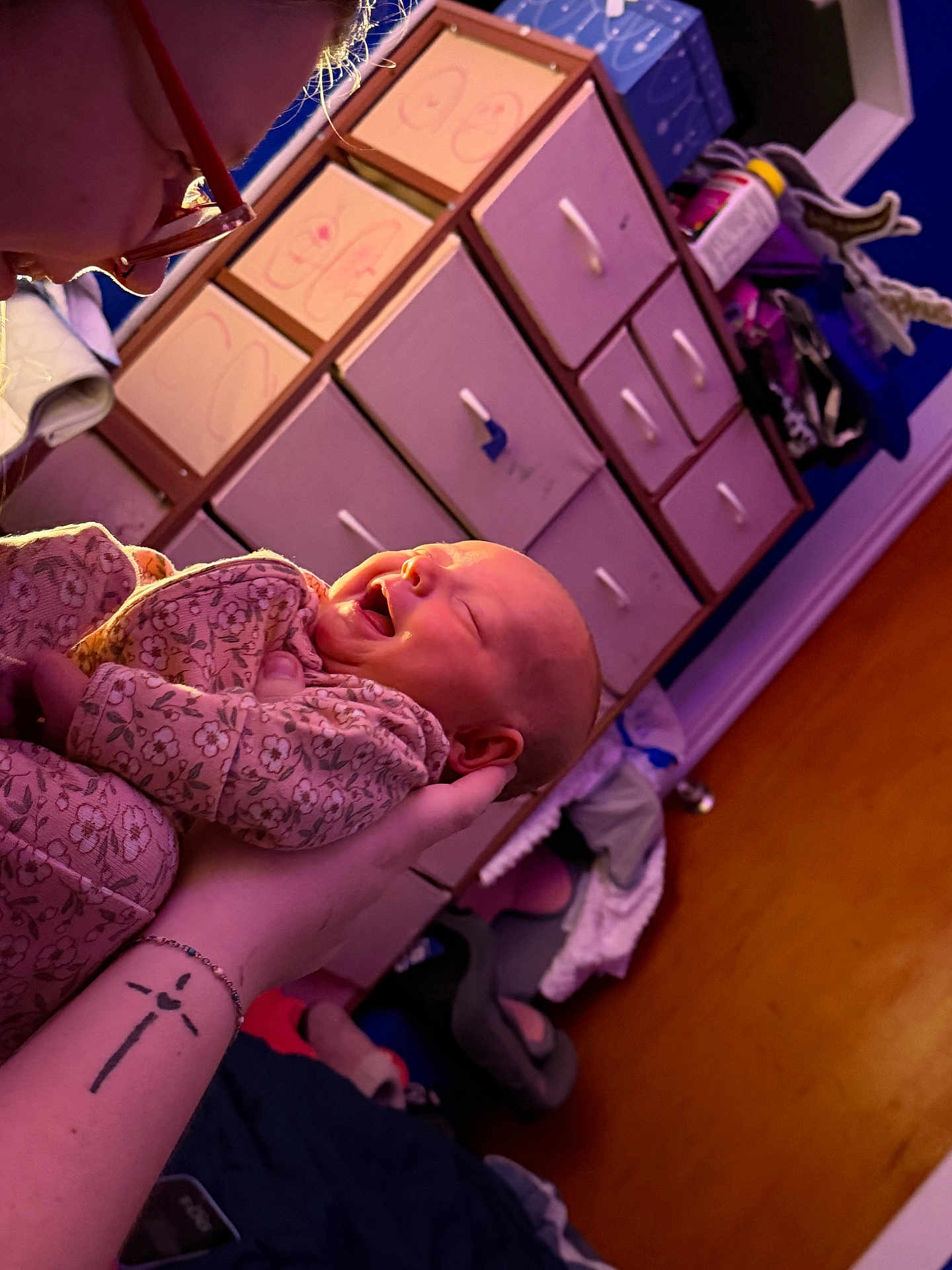 Oaklyn is registered to the contest to win money with this photo: adult, baby, bed, blanket, clothing, cozy, door, drawer, furniture, glasses, hand, holding, indoor, laughing, pajamas, person, room, smiling, tattoo, warm_light