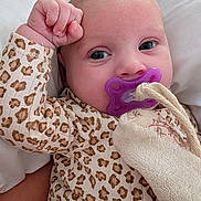 Léanne participe au concours pour gagner de l'argent avec cette photo : baby, infant, pacifier, leopard_print, clothing, blanket, hand, face, pillow, soft_toy, cute, closeup, person, young_child, sleepwear, resting, indoors, skin, head, expression