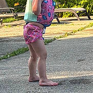Haisley is registered to the contest to win money with this photo: child, smiling, barefoot, swim_vest, pink_shorts, outdoor, poolside, flowers, orange_lilies, lawn_chair, sunlight, happy, summer, nature, tree, grass, concrete, person, young_child, playful