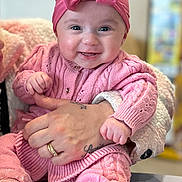 Amyrah is registered to the contest to win money with this photo: accessories, baby, bodypart, cap, clothing, couch, face, finger, furniture, hand, happy, hat, head, jewelry, knitwear, person, photography, portrait, smile, sweater