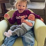Joseph is registered to the contest to win money with this photo: toddler, newborn, child, sibling, armchair, green_checkered, indoor, living_room, smiling, tongue_out, pigtails, cozy_clothing, baby, happy, cute, family, casual, couch, wooden_table, natural_light