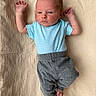 baby, newborn, infant, blue_shirt, gray_pants, lying_down, blanket, beige, curious, arms_up, small_hands, tiny_feet, portrait, indoor, soft_texture, cute, child, person, clothing, relaxed