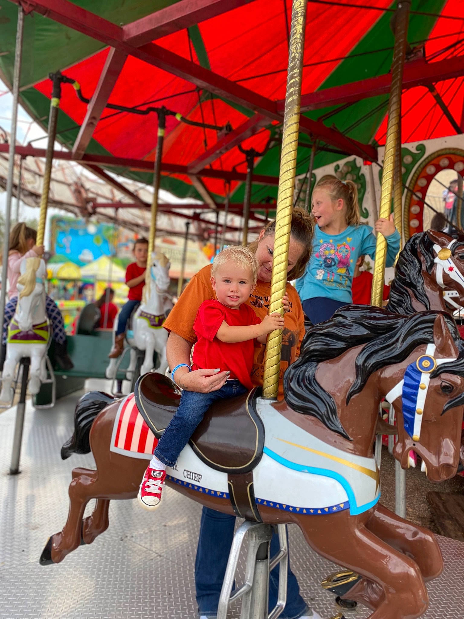 Carson is registered to the contest to win money with this photo: amusement_ride, blurred, bridle, carousel, child, event, fair, fun, horse, horse_supplies, horse_tack, leisure, nonbuilding_structure, pack_animal, person, playground, pole, recreation, rein, saddle