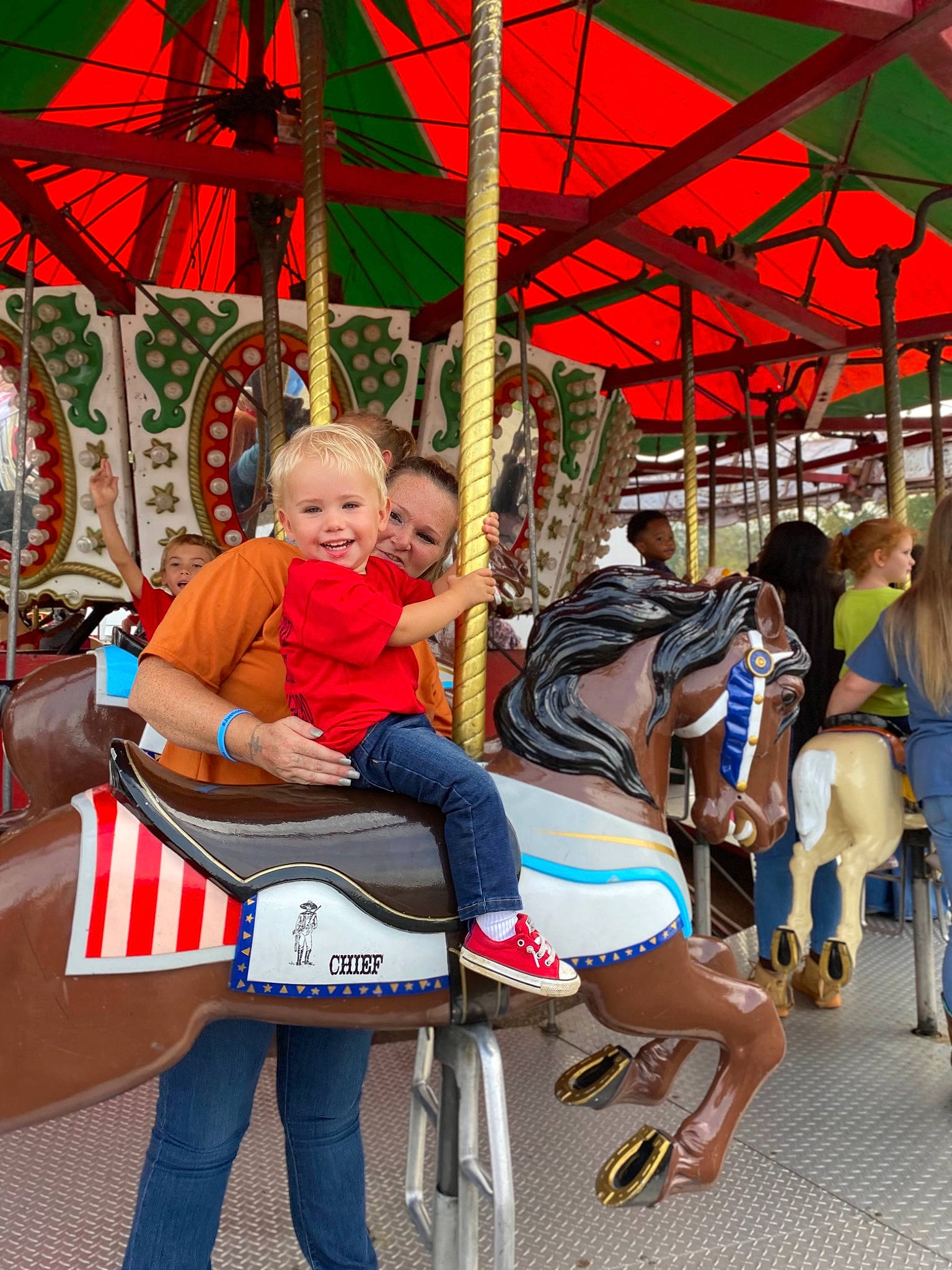 Carson joined the competition — help win amazing prizes! amusement_ride, bridle, carousel, child, event, fun, horse, horse_supplies, horse_tack, human_settlement, joy, leisure, outdoor_recreation, person, photograph, playground, recreation, temple, toddler, tree